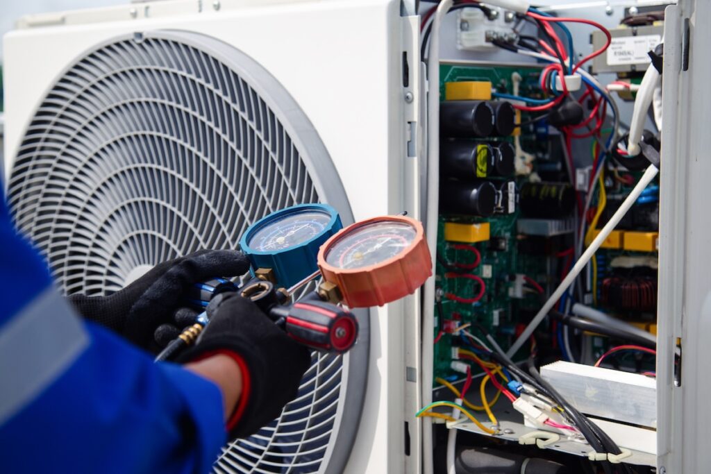 Air conditioner service .The air conditioner technician is using a gauge to measure the refrigerant pressure. air compressor.