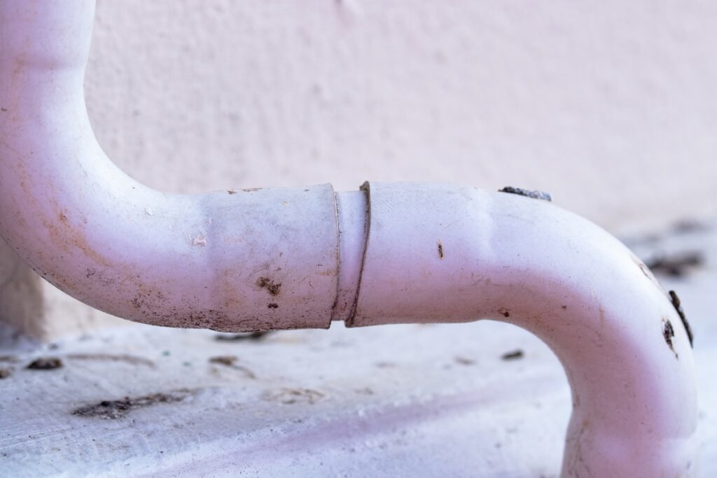 White plastic air conditioner drain pipe duct, wiring and plumbing in mall. Air conditioner pipe, wiring pipe, and plumbing pipe system. Air ducts and water pipes are installed on wall at outdoor. how to clean AC drain line