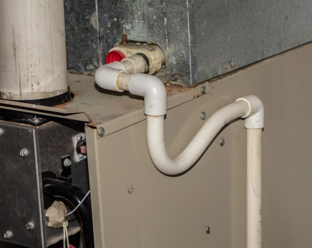 The image shows the curved pipe and P-trap, illustrating the specific component that requires cleaning when learning how to clean AC drain line.