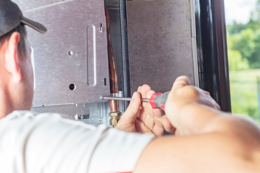 The master sets up a gas boiler, which weighs on the wall. The front dashboard is open. The removal and installation of gas nozzles for gas supply.