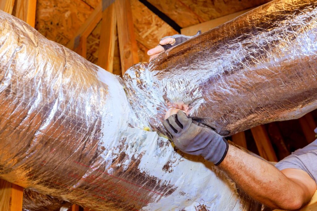 Workers are sealing duct connections in attic to ensure proper airflow, energy efficiency at home