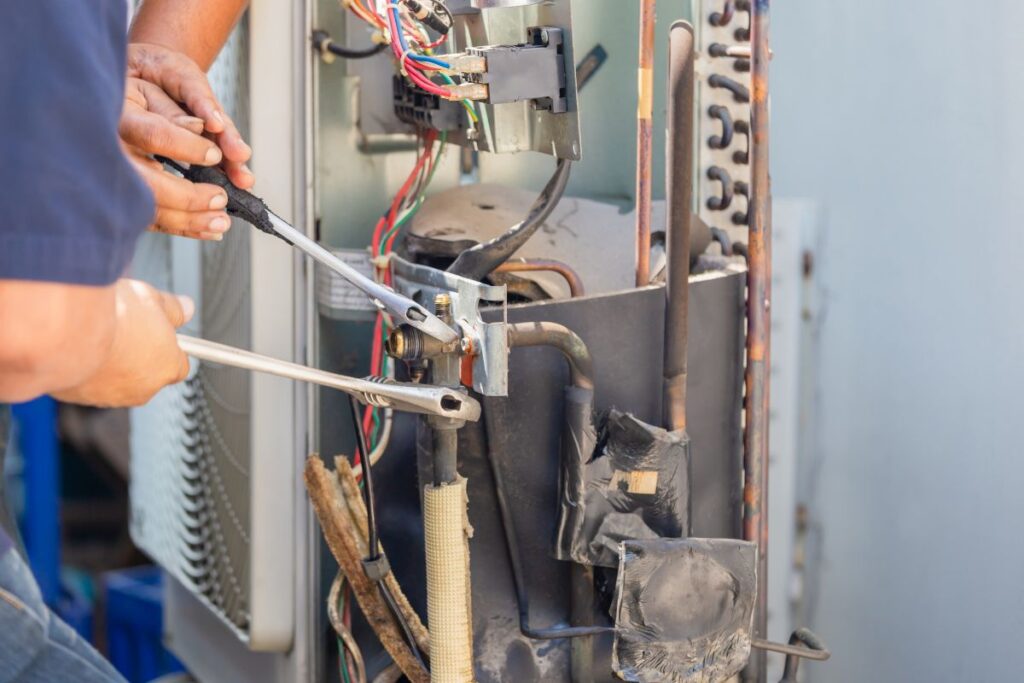 Technician man using a wrench fixing modern air conditioning system