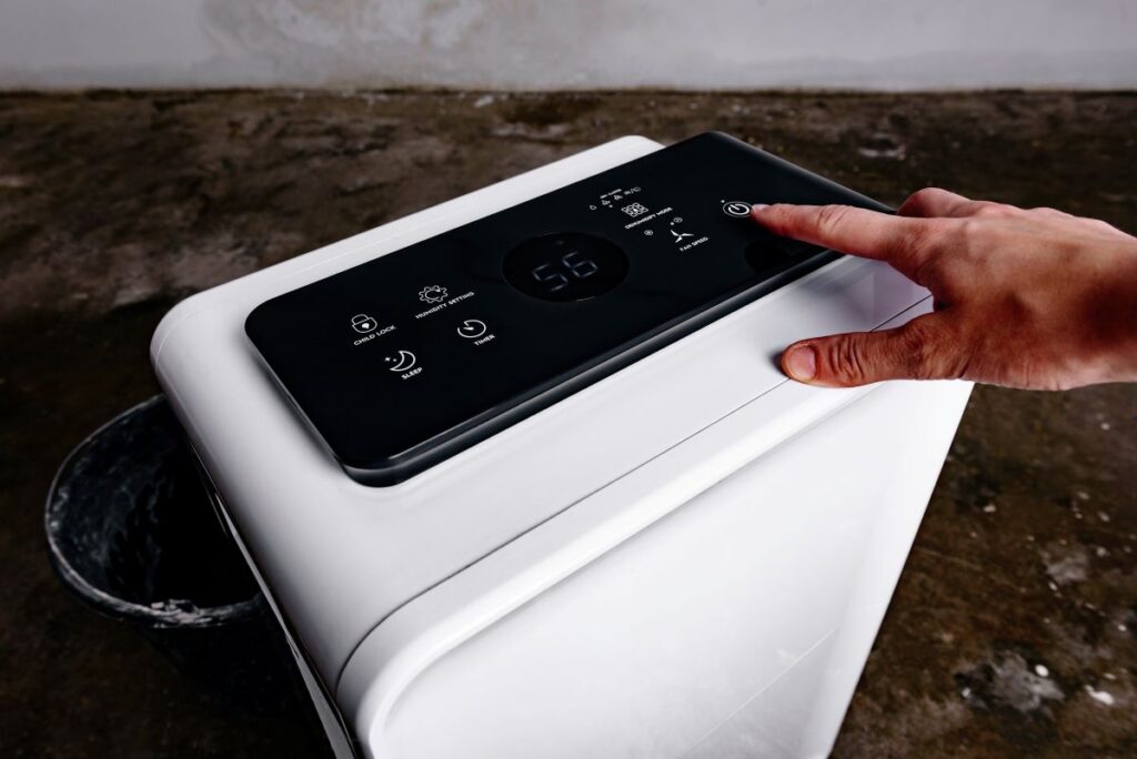 Woman's hand turning on a dehumidifier in the basement