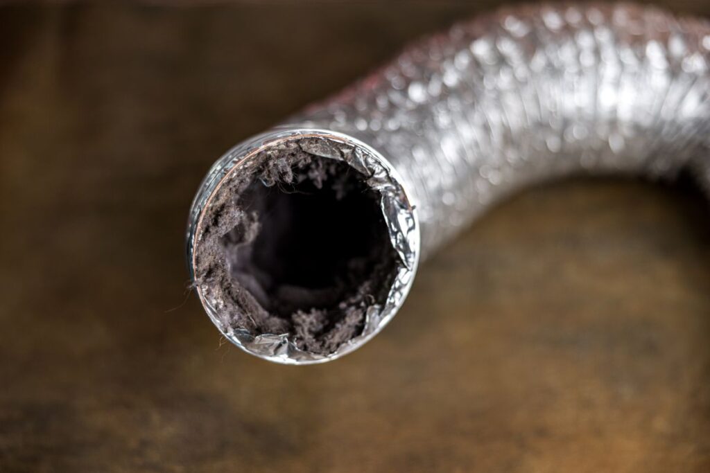 A dirty laundry flexible aluminum dryer vent duct ductwork filled with lint, dust and dirt